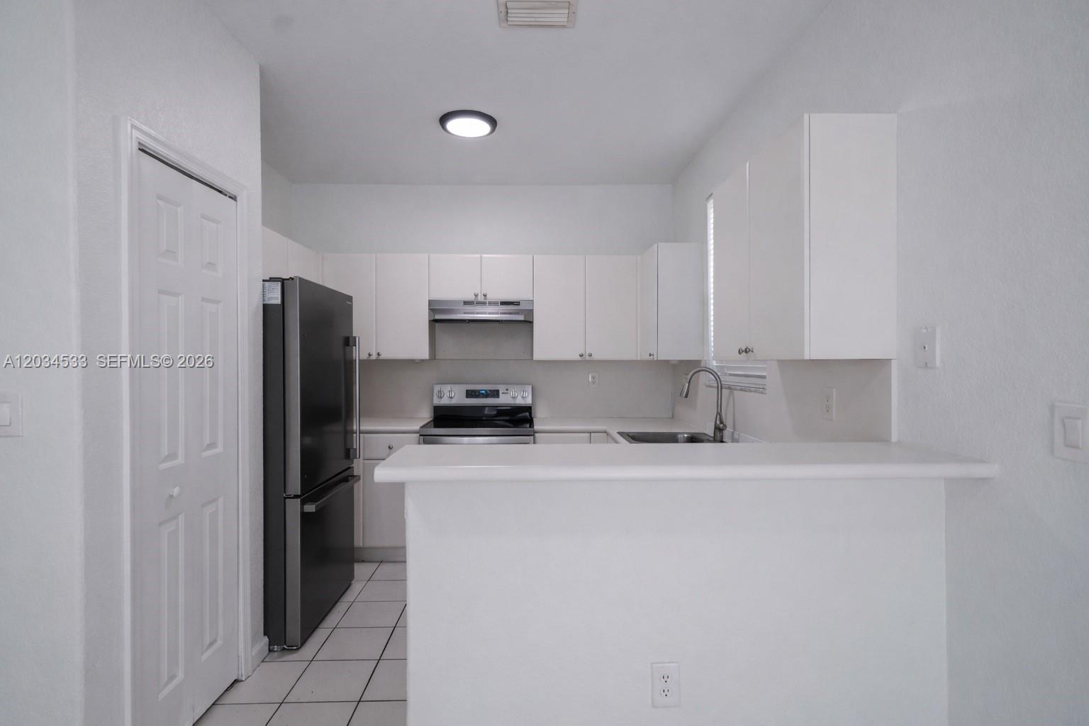 A white kitchen features stainless steel appliances, white cabinetry, and a breakfast bar — 1441 SE 24th Ct # 257, Homestead FL 33035, HOMESTEAD, FL