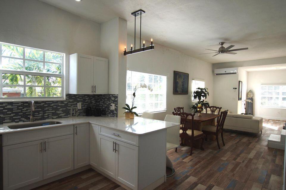 A kitchen with white cabinets and a peninsula opens into a dining and living area — 331 NW 1st Avenue, Boynton Beach FL 33435, BOYNTON BEACH, FL