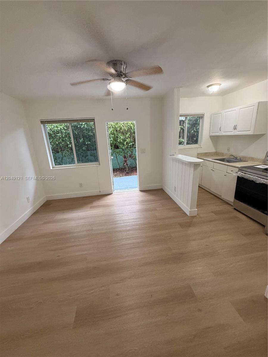 An open-concept kitchen and living area features light wood-look flooring and a ceiling fan — 469 SW 3rd St # 4, Miami FL 33130, MIAMI, FL