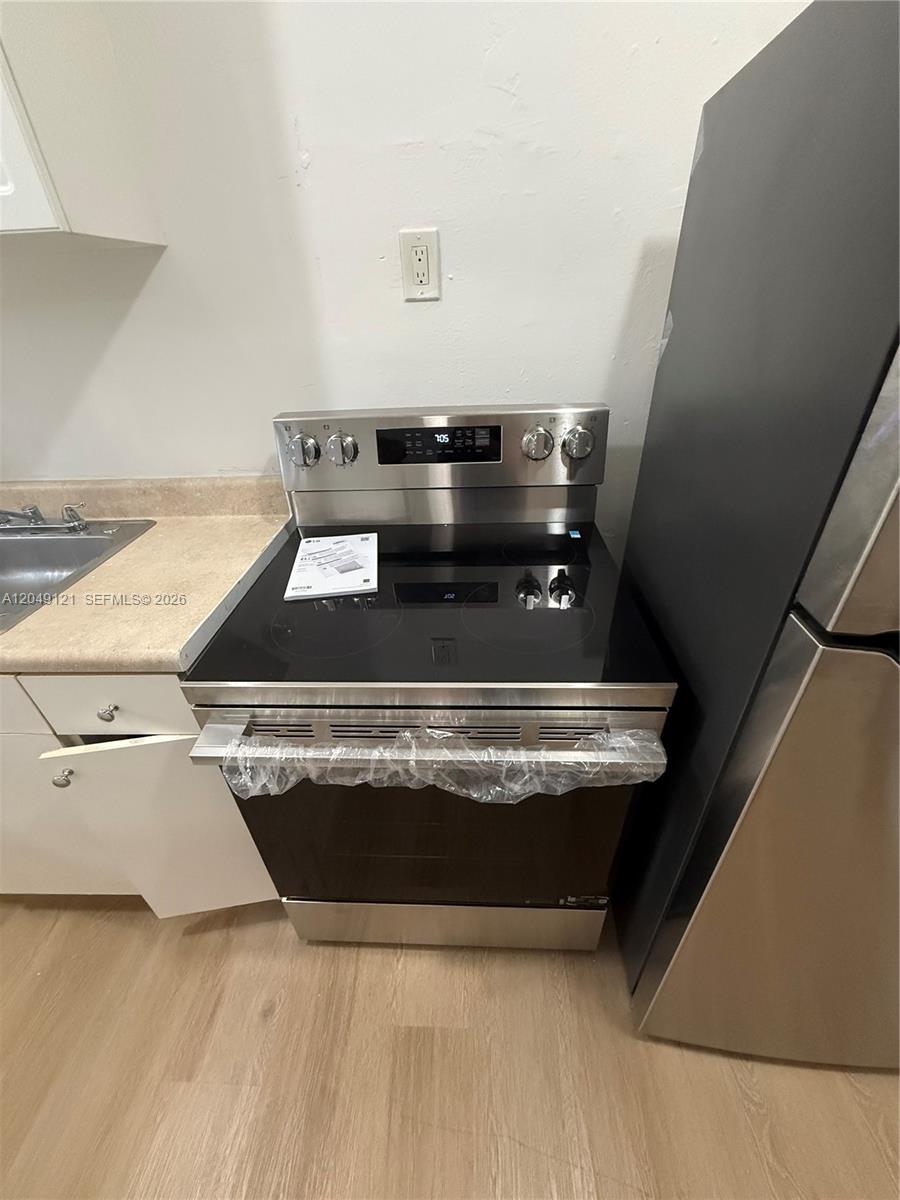 A stainless steel electric range is positioned between a kitchen sink and a refrigerator — 469 SW 3rd St # 4, Miami FL 33130, MIAMI, FL