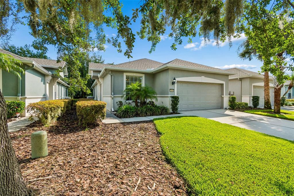 A single-story suburban house with a gray exterior, a two-car garage, and a manicured lawn — 10448 48TH COURT E, PARRISH, FL
