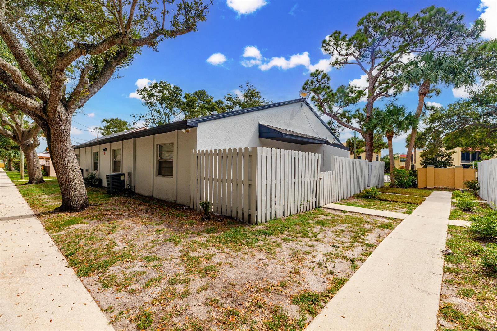 A white single-story building with a fenced patio area and a sidewalk in the foreground — 2007 Oleander Boulevard Apt D, Fort Pierce FL 34950, FORT PIERCE, FL
