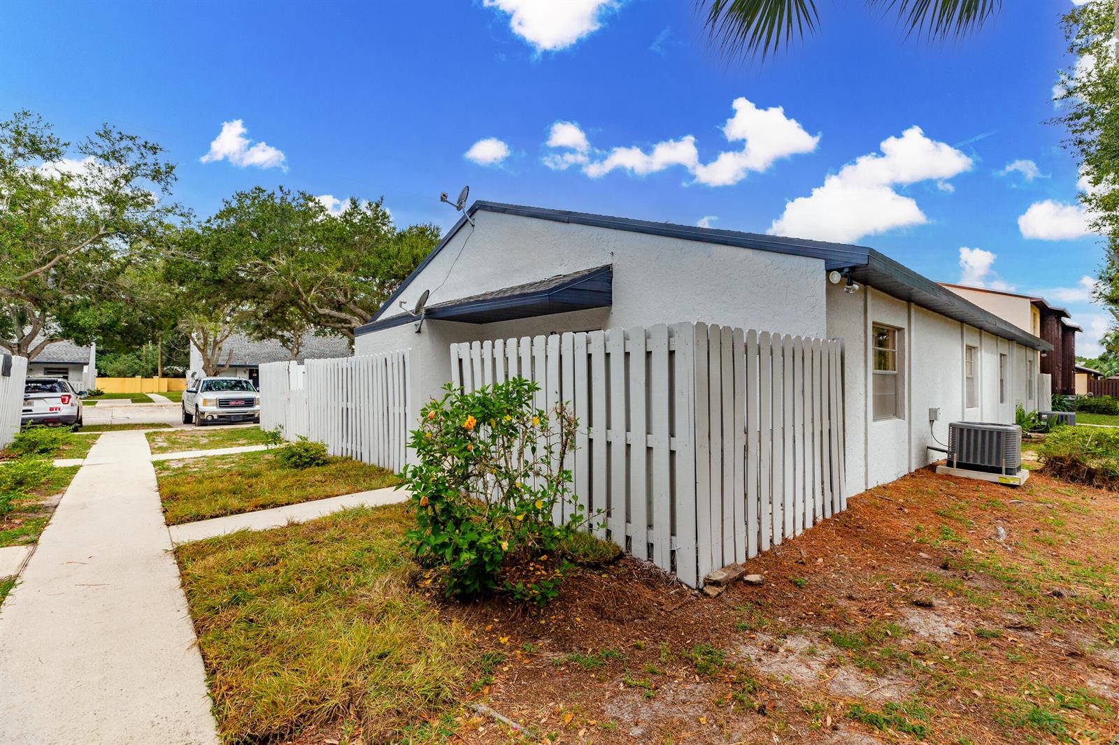 The exterior of a single-story home features a white fence, a small yard, and landscaping — 2007 Oleander Boulevard Apt D, Fort Pierce FL 34950, FORT PIERCE, FL