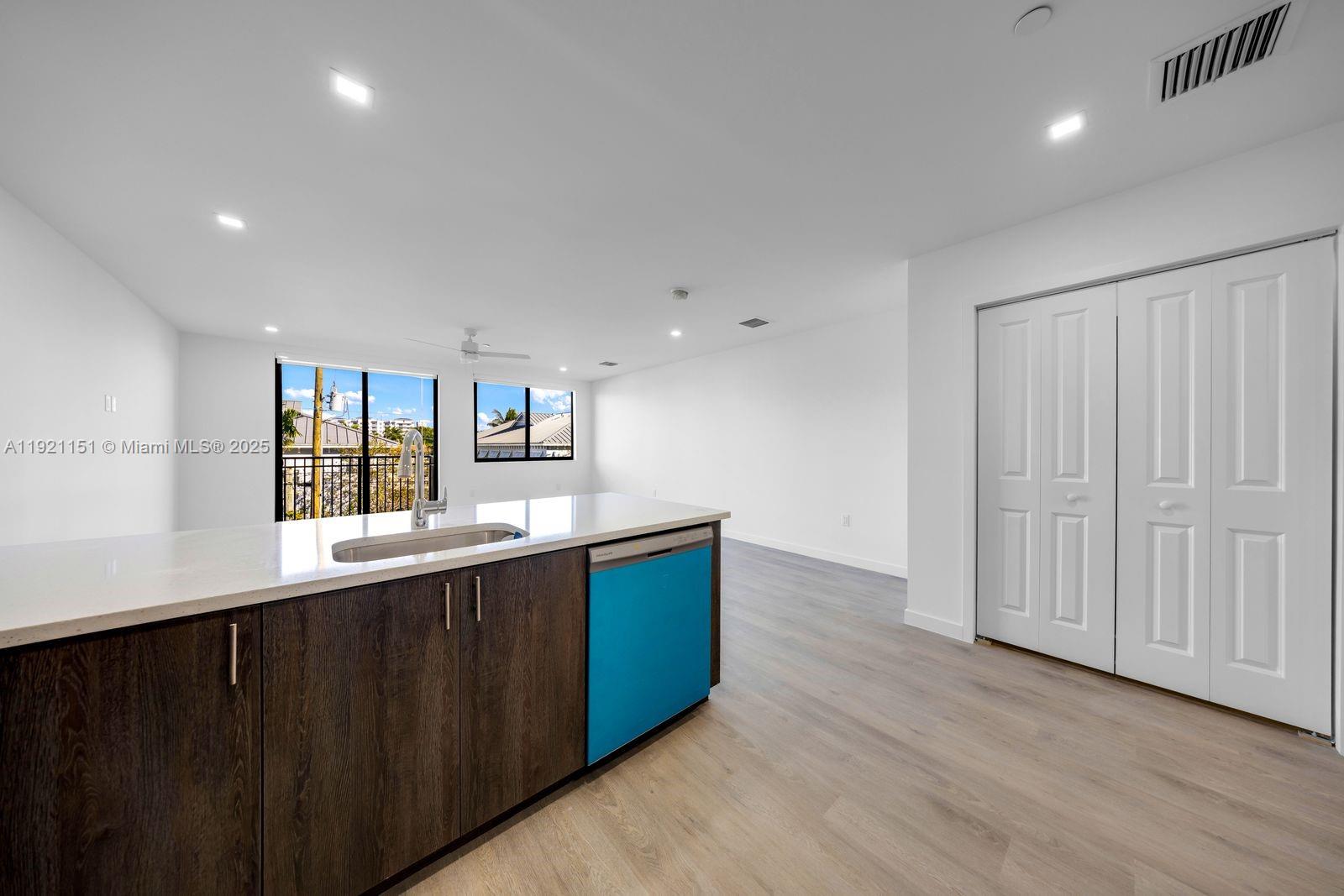 A modern kitchen features dark wood cabinets, white countertops, and a blue dishwasher — 20 NE 19th Ave # 210, Pompano Beach FL 33060, POMPANO BEACH, FL