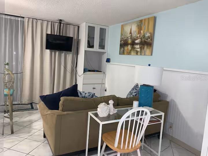 A living room features a tan sofa, a small desk with a chair, and a television — 800 BAYWAY BOULEVARD UNIT 26, CLEARWATER BEACH, FL