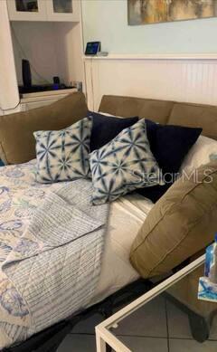 A view of a sofa bed with patterned pillows and a shell-print quilt — 800 BAYWAY BOULEVARD UNIT 26, CLEARWATER BEACH, FL