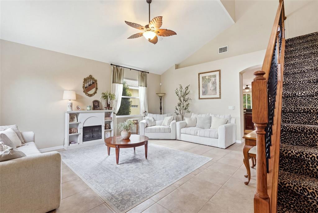A living room features a fireplace, white furniture, a patterned rug, and a carpeted staircase — 3565 MALAGROTTA CIRCLE, CAPE CORAL, FL