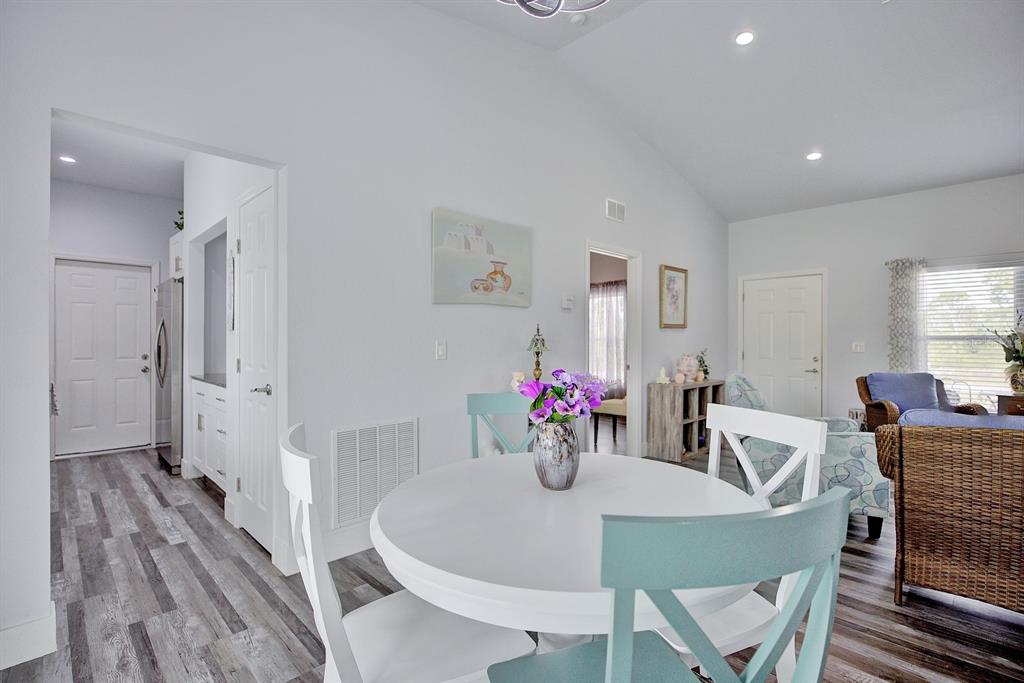 A dining area features a white round table, light blue chairs, and wood-look flooring — 230 E CANAL WAY NE, LAKE PLACID, FL