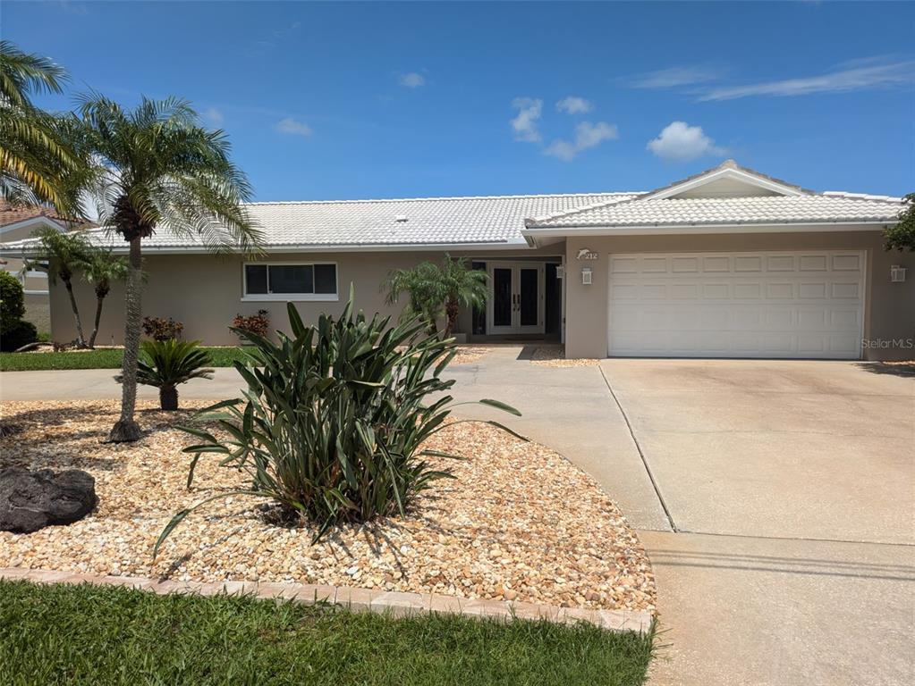 A single-story house with a white tile roof, beige exterior, and a two-car garage — 212 POINCIANA LANE, LARGO, FL
