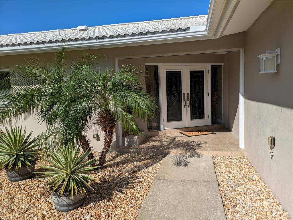 A concrete walkway leads to a white double front door with glass inserts and sidelights — 212 POINCIANA LANE, LARGO, FL