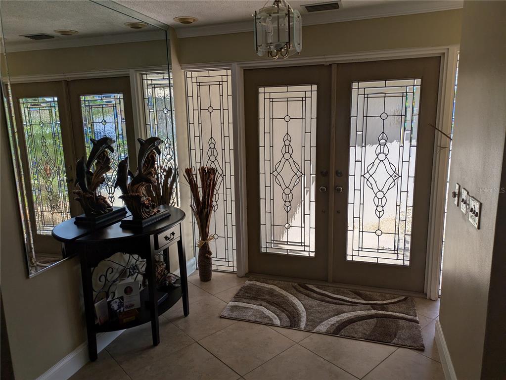 An entryway features double glass-paneled doors, a tiled floor, and a decorative console table — 212 POINCIANA LANE, LARGO, FL
