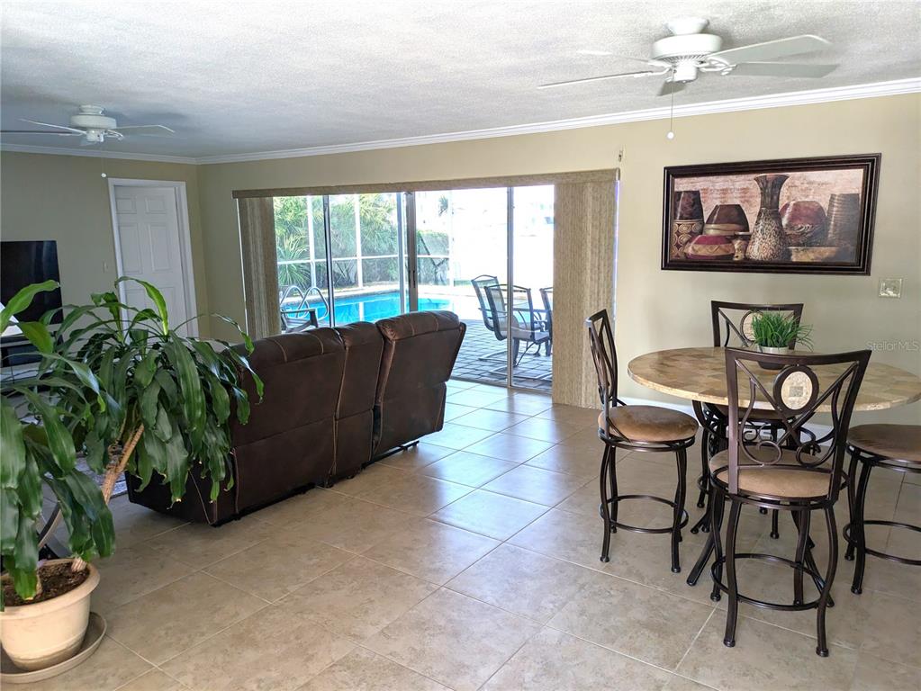 A living and dining area with tile floors, a brown sofa, and sliding glass doors — 212 POINCIANA LANE, LARGO, FL