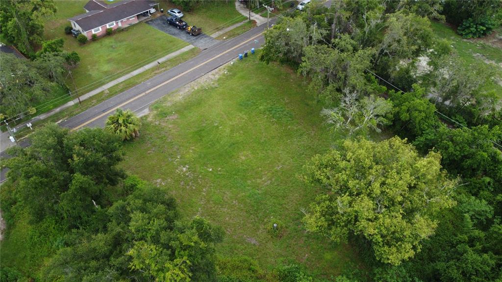 An aerial view shows a vacant, grassy rectangular lot bordered by a road and trees — 10616 DAVIS ROAD, TAMPA, FL