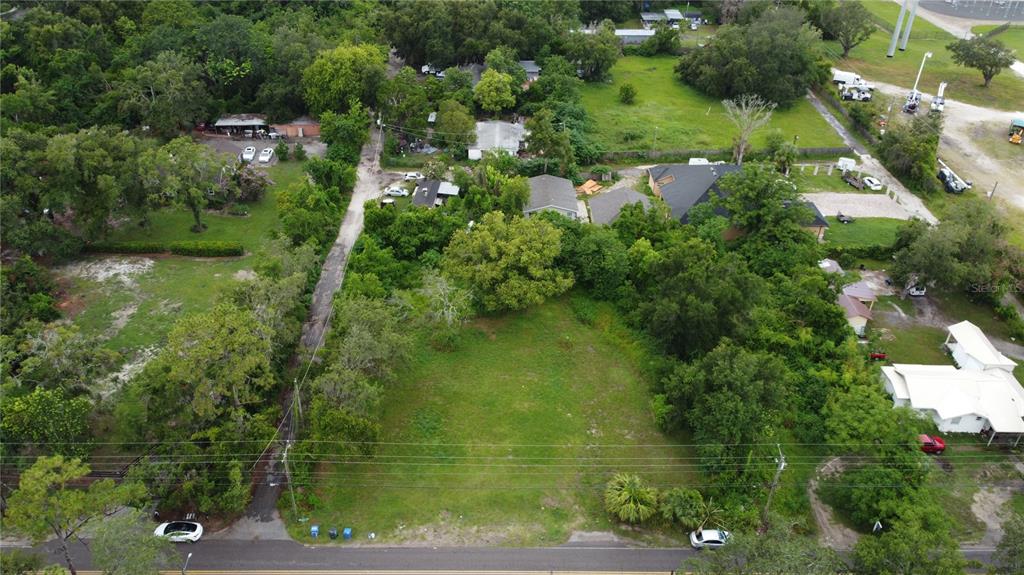An aerial view shows a vacant, grassy rectangular lot bordered by trees and residential houses — 10616 DAVIS ROAD, TAMPA, FL