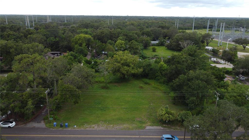 An aerial view shows a vacant, grassy lot bordered by trees and a paved road — 10616 DAVIS ROAD, TAMPA, FL