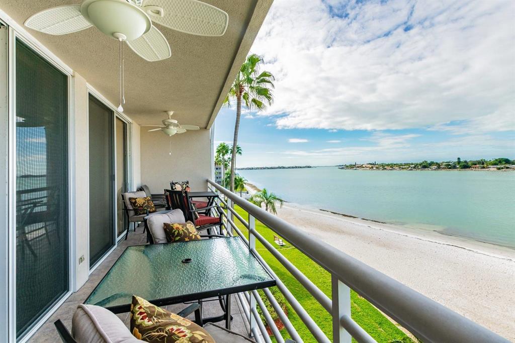 A balcony with outdoor furniture overlooks a sandy beach and a calm body of water — 5701 BAHIA DEL MAR CIRCLE UNIT 403, ST PETERSBURG, FL