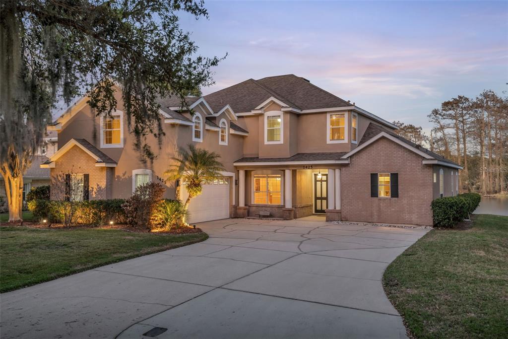 A two-story house with a brick and stucco exterior, a concrete driveway, and a front porch — 1425 RIVIERA DRIVE, KISSIMMEE, FL