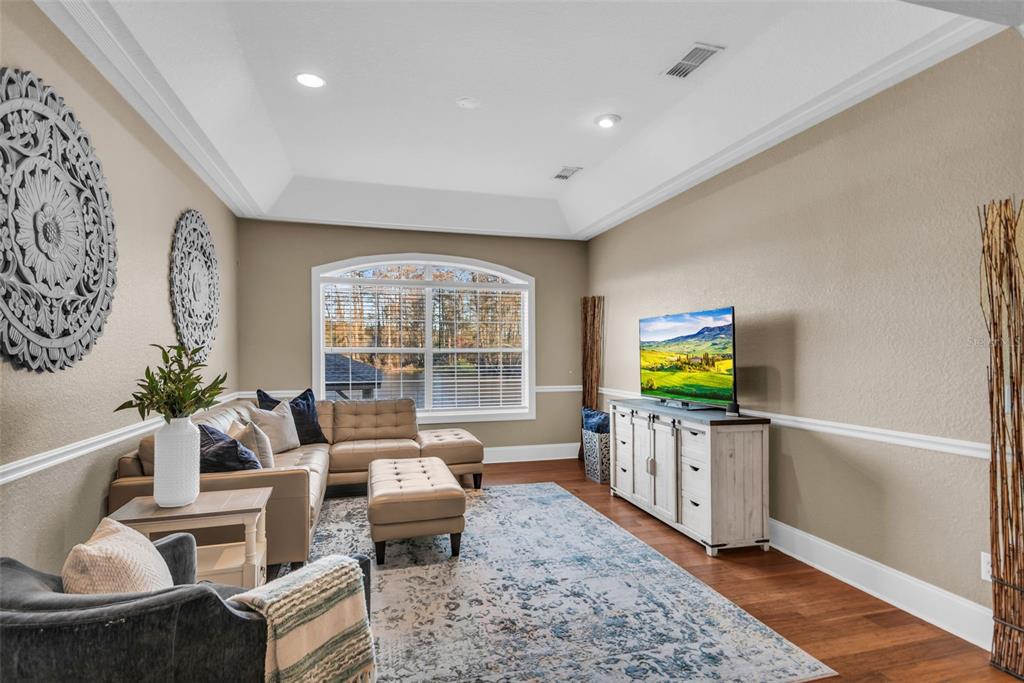 A living room features a tan sectional sofa, a television on a console, and large windows — 1425 RIVIERA DRIVE, KISSIMMEE, FL
