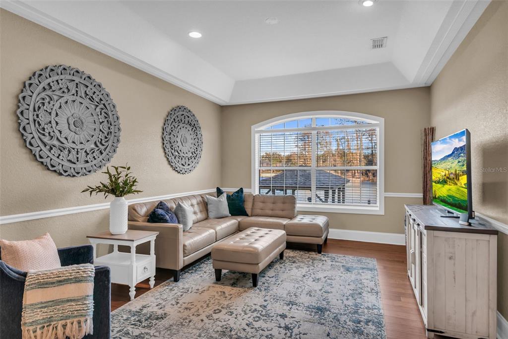 A living room features a tan sectional sofa, a patterned rug, and two circular wall decorations — 1425 RIVIERA DRIVE, KISSIMMEE, FL