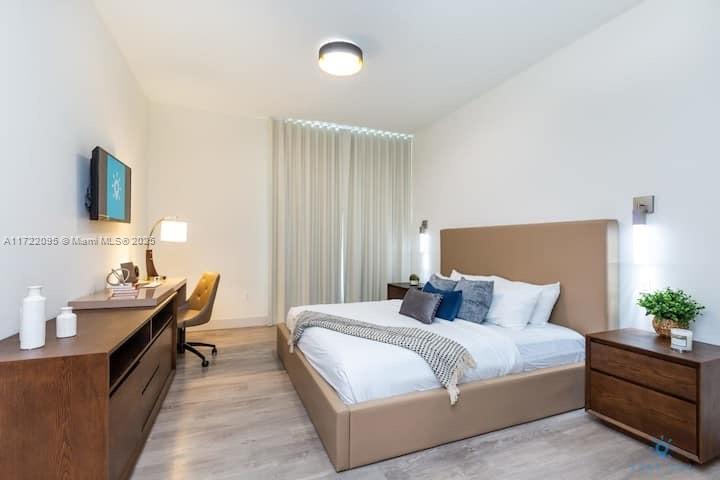 A bedroom features a bed with a tan headboard, a wooden desk, and light flooring — 777 N Ocean Dr # S228, Hollywood FL 33019, HOLLYWOOD, FL
