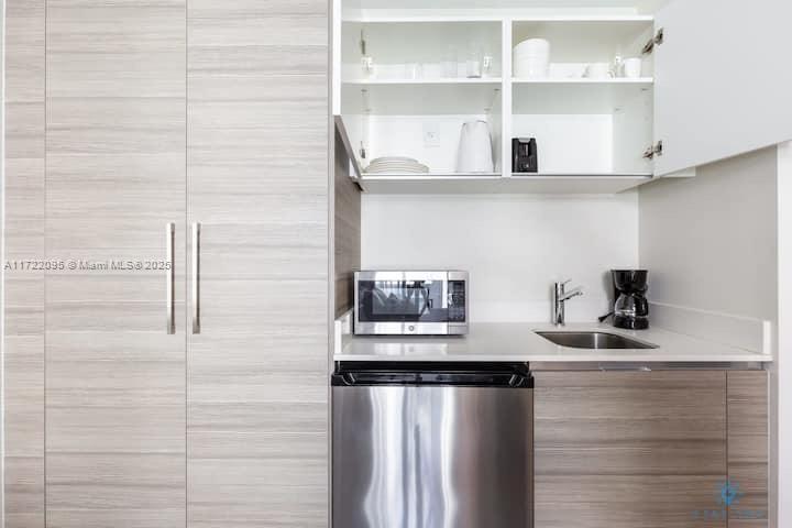 A kitchenette features light wood cabinetry, a stainless steel microwave, a mini-fridge, and a sink — 777 N Ocean Dr # S228, Hollywood FL 33019, HOLLYWOOD, FL