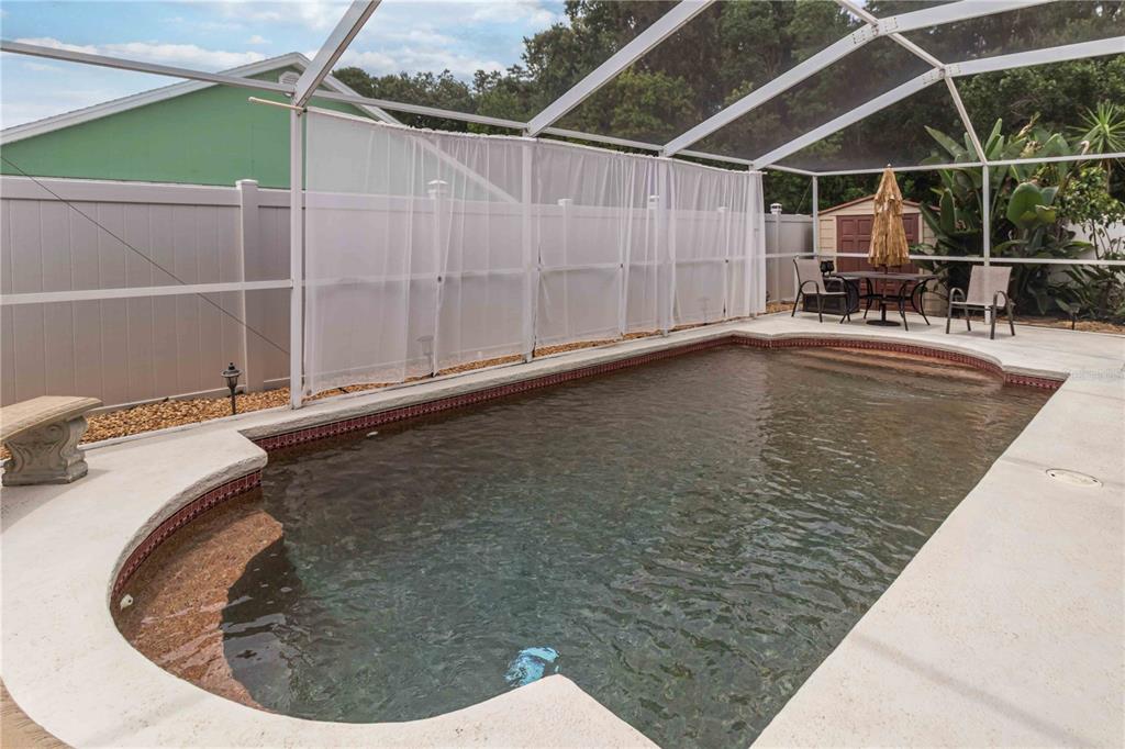 A screened-in swimming pool with a concrete deck and a white privacy fence — 9714 STONE MOUNTAIN PLACE, TAMPA, FL