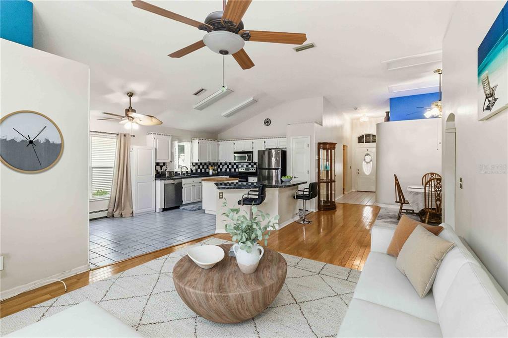 An open-concept living room with a white sofa faces a kitchen featuring black-and-white tile backsplashes — 9714 STONE MOUNTAIN PLACE, TAMPA, FL