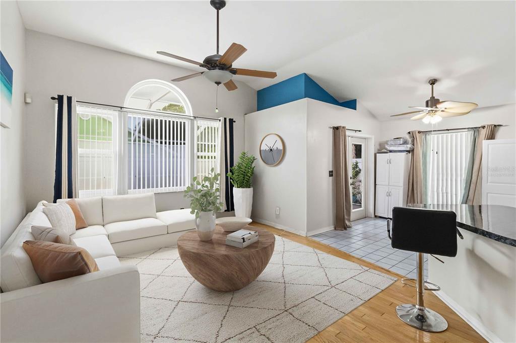 A living room features a white sectional sofa, a round wooden coffee table, and ceiling fans — 9714 STONE MOUNTAIN PLACE, TAMPA, FL