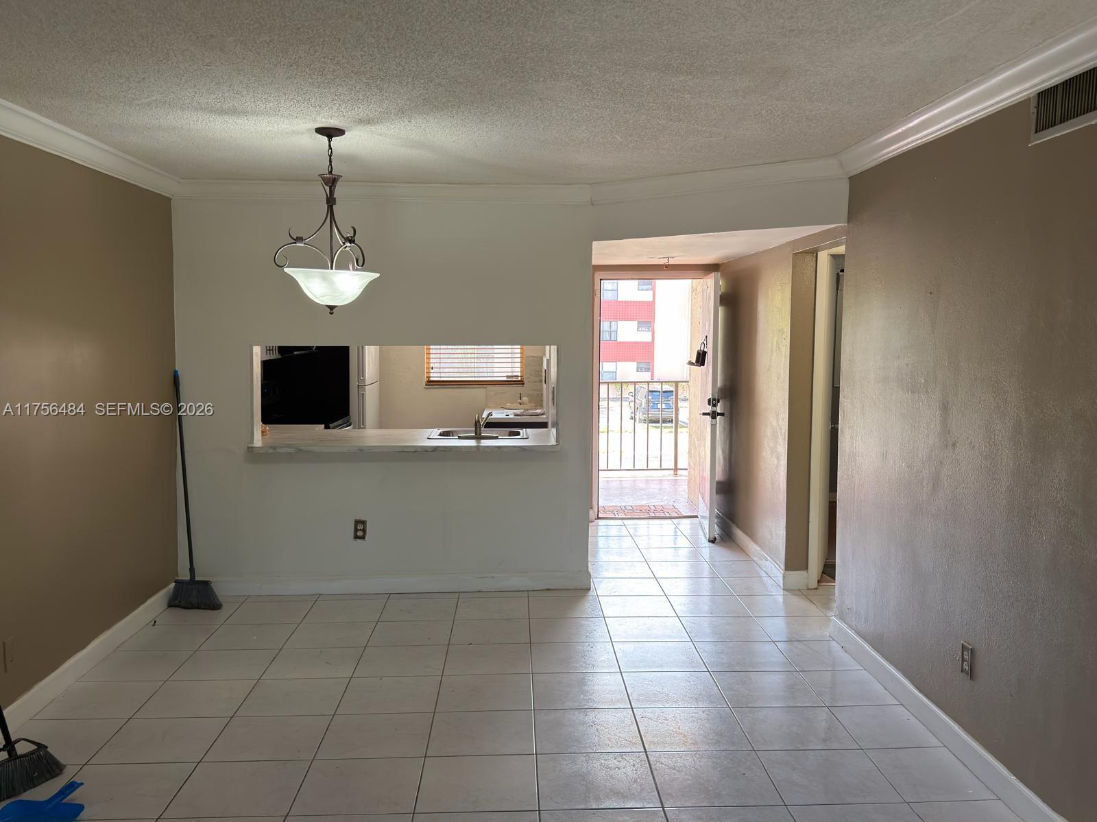 An interior view shows a tiled dining area with a pass-through window to the kitchen — 3400 Foxcroft Rd # 212, Miramar FL 33025, MIRAMAR, FL