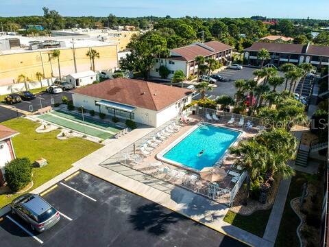 An aerial view shows a swimming pool, shuffleboard court, and apartment buildings with parking lots — 1531 PLACIDA ROAD UNIT 203, ENGLEWOOD, FL