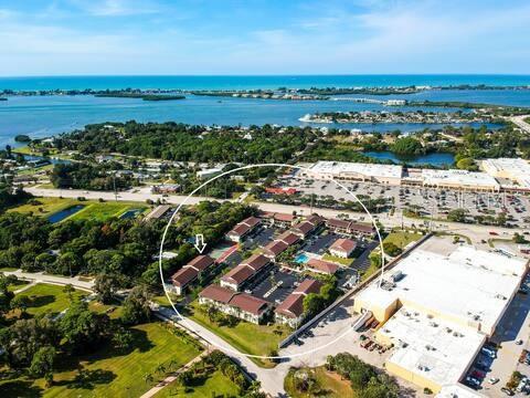 Aerial view of a multi-building apartment complex surrounded by green space and nearby commercial areas — 1531 PLACIDA ROAD UNIT 203, ENGLEWOOD, FL