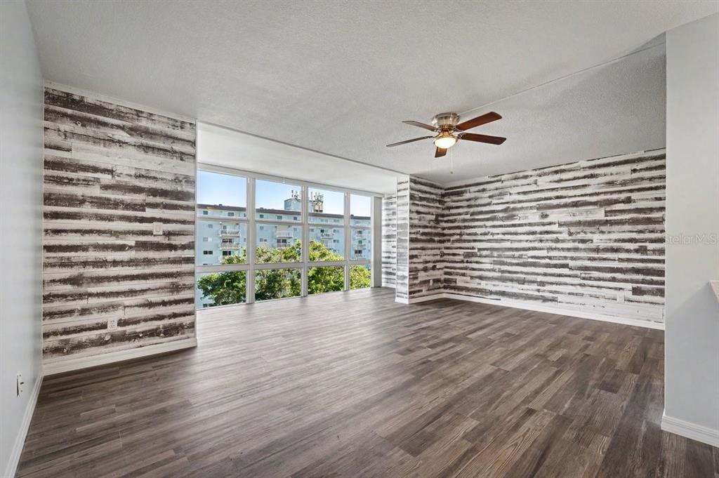 An empty room with wood-look flooring, rustic horizontal wall paneling, and large floor-to-ceiling windows — 1224 S PENINSULA DRIVE UNIT 621, DAYTONA BEACH, FL