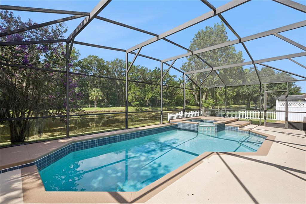 A screened-in swimming pool and spa overlook a pond and wooded area — 5703 AUTUMN CHASE CIRCLE, SANFORD, FL