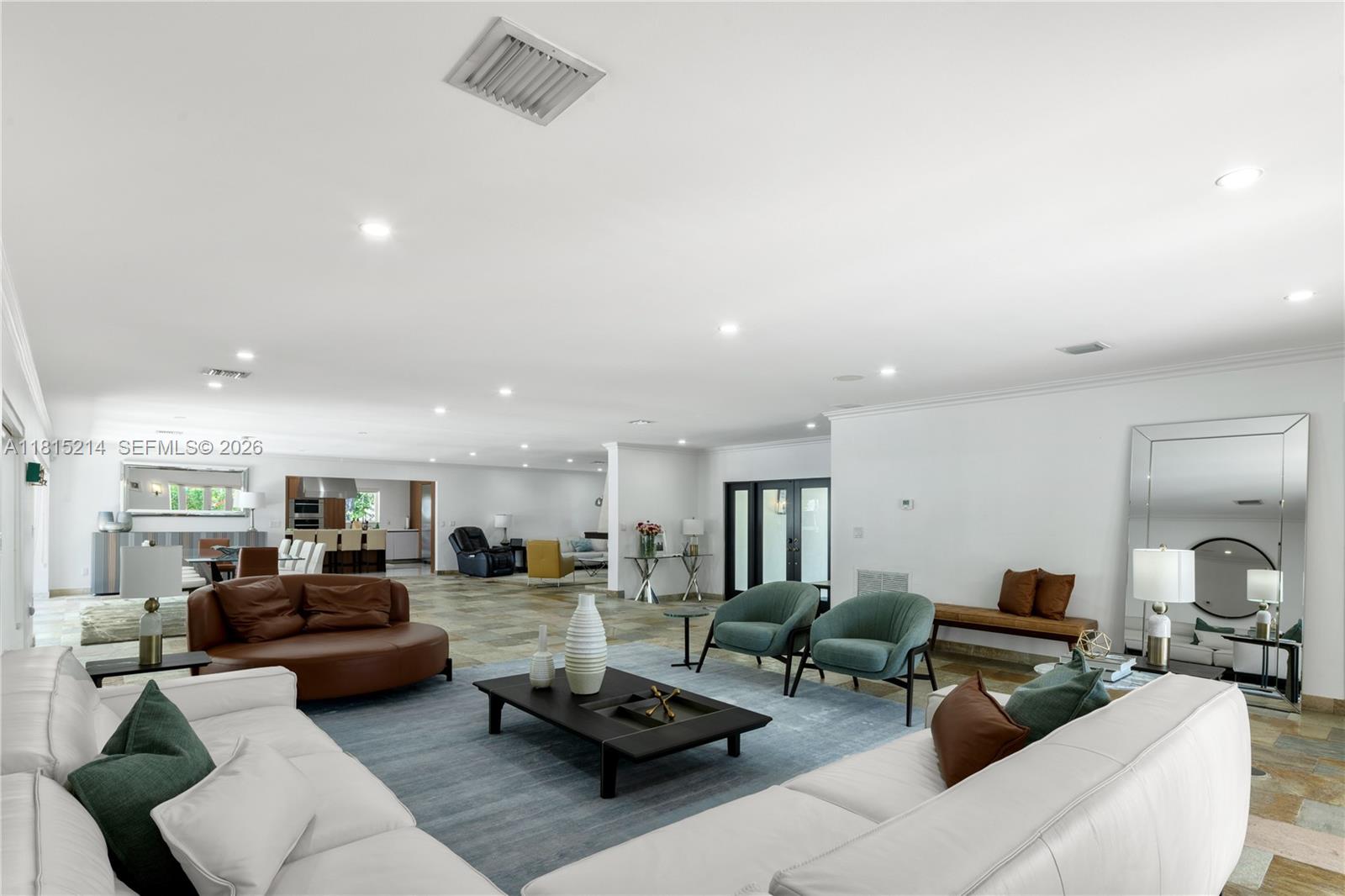 A spacious living room features white sofas, a blue area rug, and tile flooring — 435 Marquesa Dr, Coral Gables FL 33156, CORAL GABLES, FL