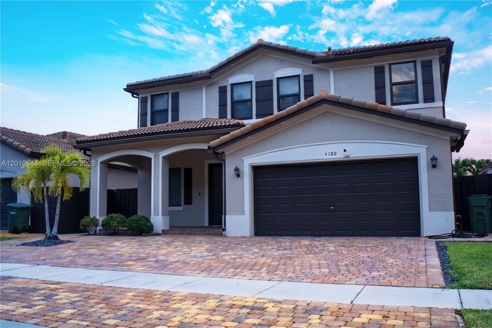 A two-story suburban house features a paved driveway, a garage, and a covered entryway — 4180 NE 21st St, Homestead FL 33033, HOMESTEAD, FL