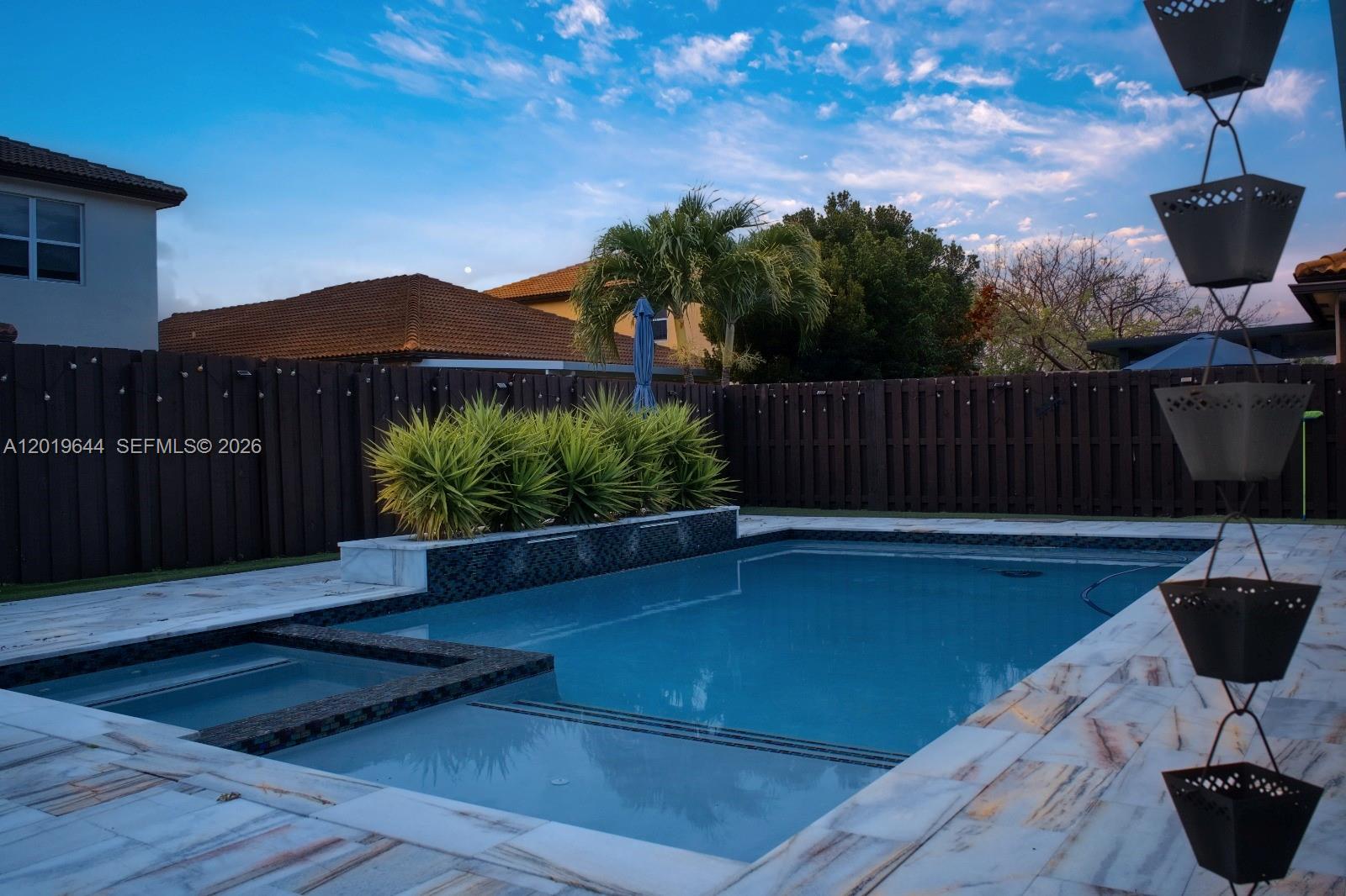 A backyard swimming pool with a spa, water feature, and a dark wooden fence — 4180 NE 21st St, Homestead FL 33033, HOMESTEAD, FL