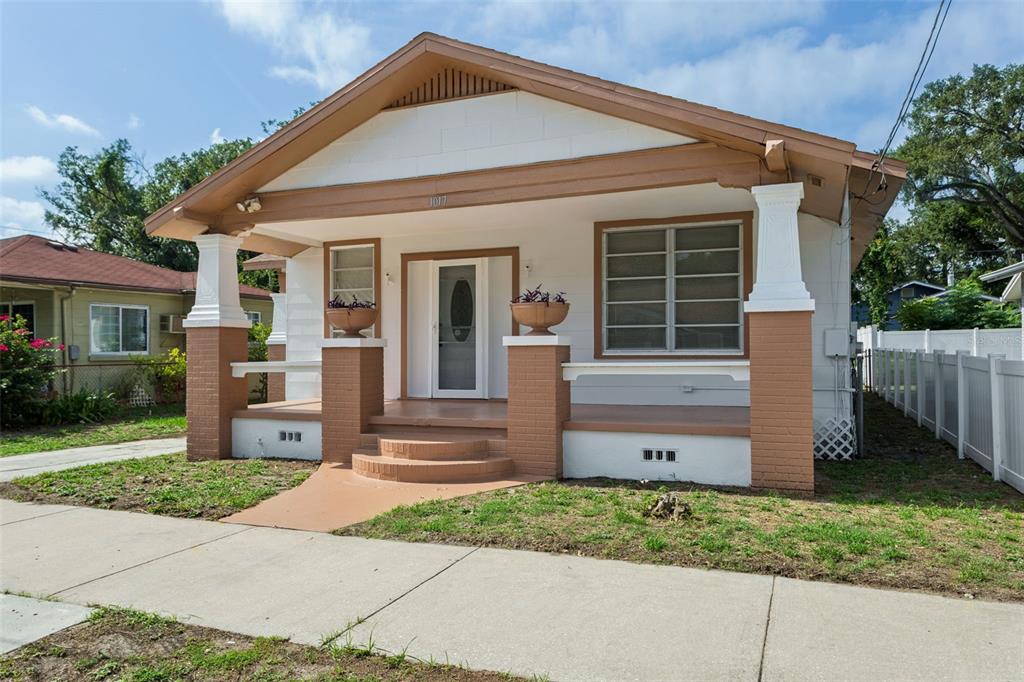 A single-story bungalow with a front porch, tan brick columns, and white siding — 1017 E 23RD AVENUE, TAMPA, FL