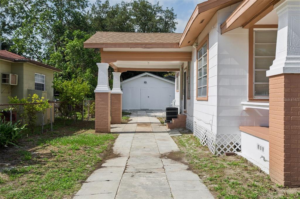 A concrete driveway leads to a detached garage beside a house with a covered porch — 1017 E 23RD AVENUE, TAMPA, FL