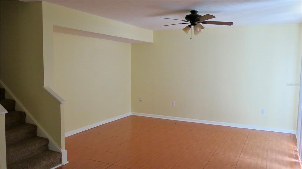 A living room with light yellow walls, wood-look flooring, and a staircase with carpeted steps — 12425 TOUCHTON DR UNIT 87, TAMPA, FL