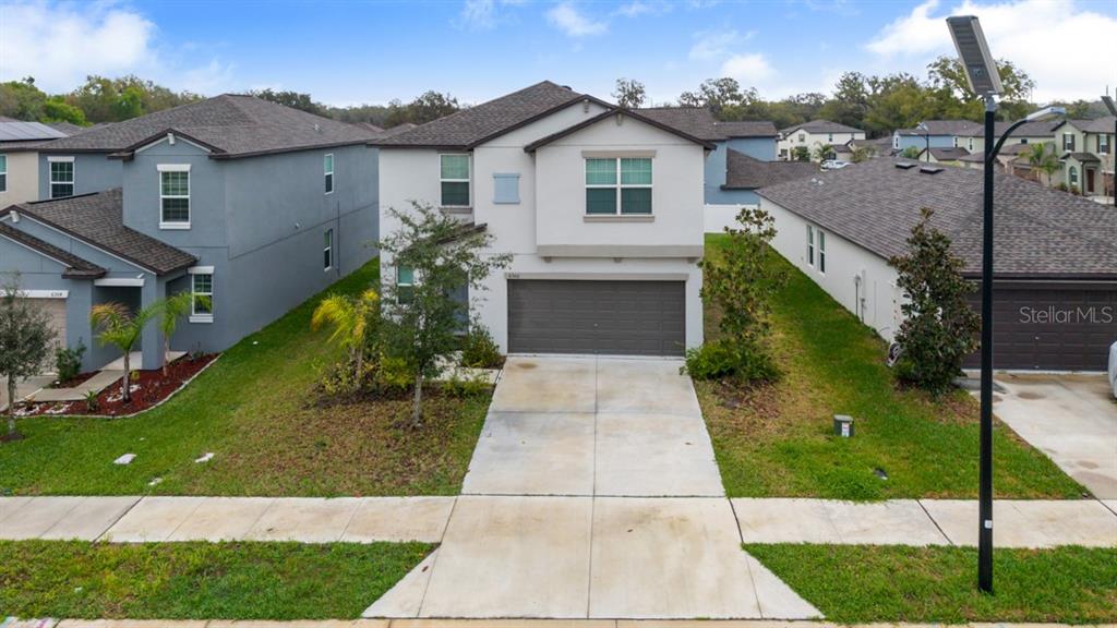 A two-story house with a gray garage, light-colored siding, and a concrete driveway — 6300 BEVERLY HILLS DRIVE, ZEPHYRHILLS, FL