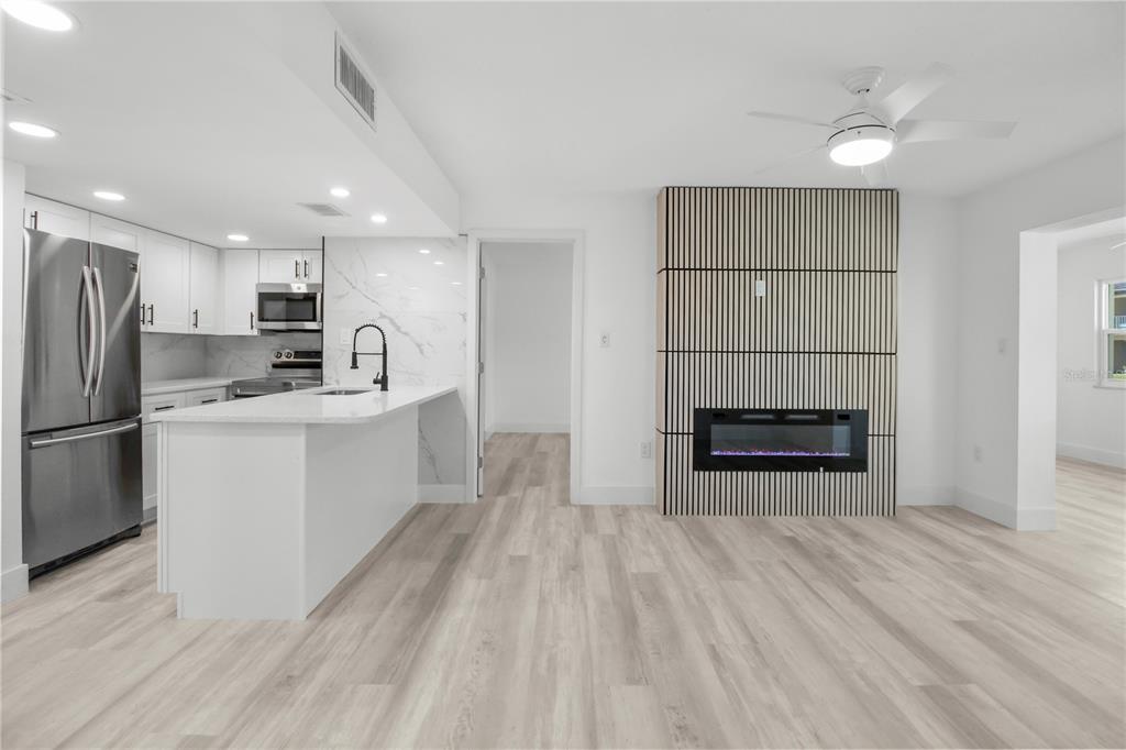 A modern kitchen with white cabinets and an island next to a slatted fireplace wall — 4754 MARINE PARKWAY UNIT 103, NEW PORT RICHEY, FL