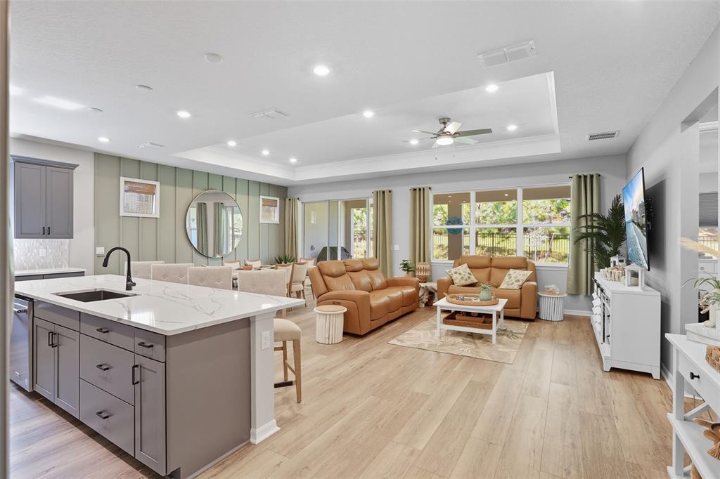 An open-concept kitchen and living area features a large island, tray ceiling, and wood flooring — 2761 TOP HILL COURT, MINNEOLA, FL