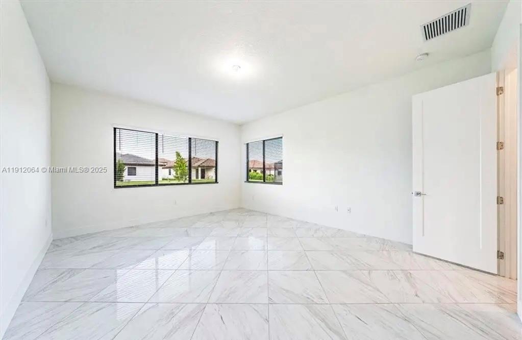 An empty room features white walls, large windows with blinds, and white marble-patterned tile flooring — 5048 GAMBERO WAY, Ave Maria FL 34142, AVE MARIA, FL