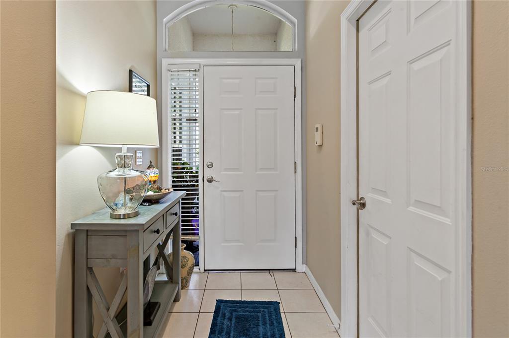 An entryway features a white front door, a console table with a lamp, and tile flooring — 19029 CALLAWAY COURT, TAMPA, FL