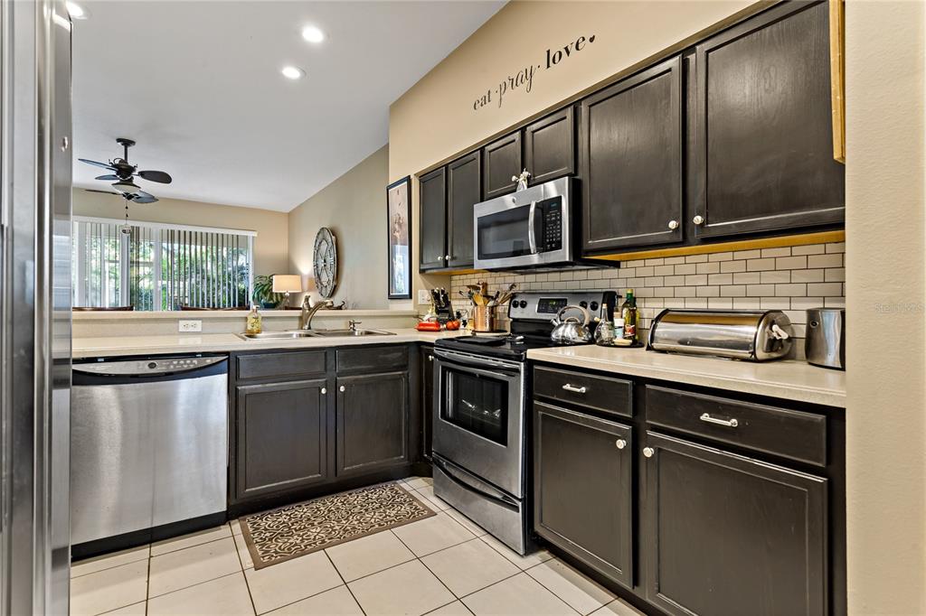 A kitchen features dark wood cabinets, stainless steel appliances, and a white subway tile backsplash — 19029 CALLAWAY COURT, TAMPA, FL