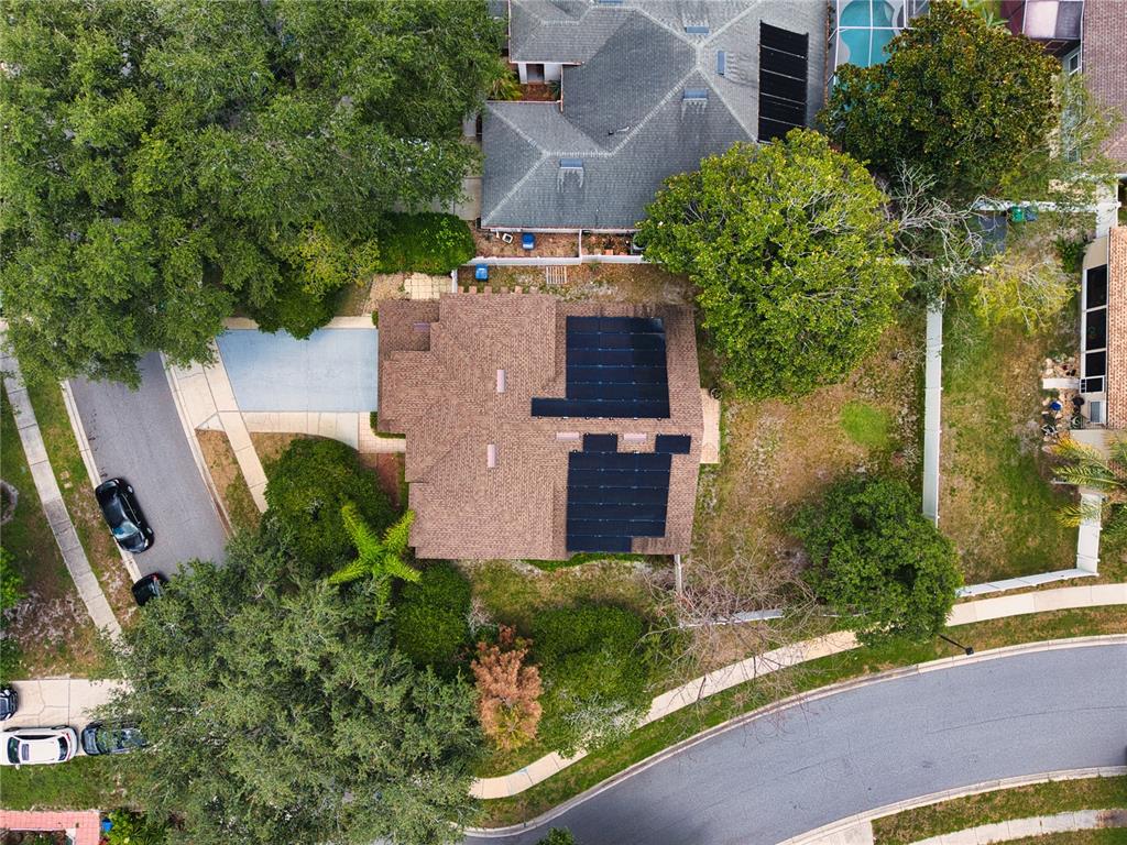 An aerial view shows a house with solar panels on the roof and surrounding landscaping — 1025 OCEANBREEZE COURT, ORLANDO, FL