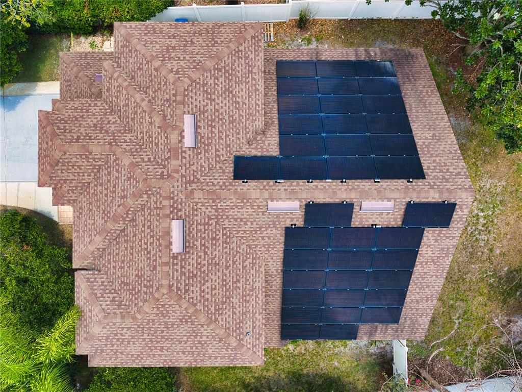 An aerial view shows a shingled roof with two large solar panel arrays installed — 1025 OCEANBREEZE COURT, ORLANDO, FL