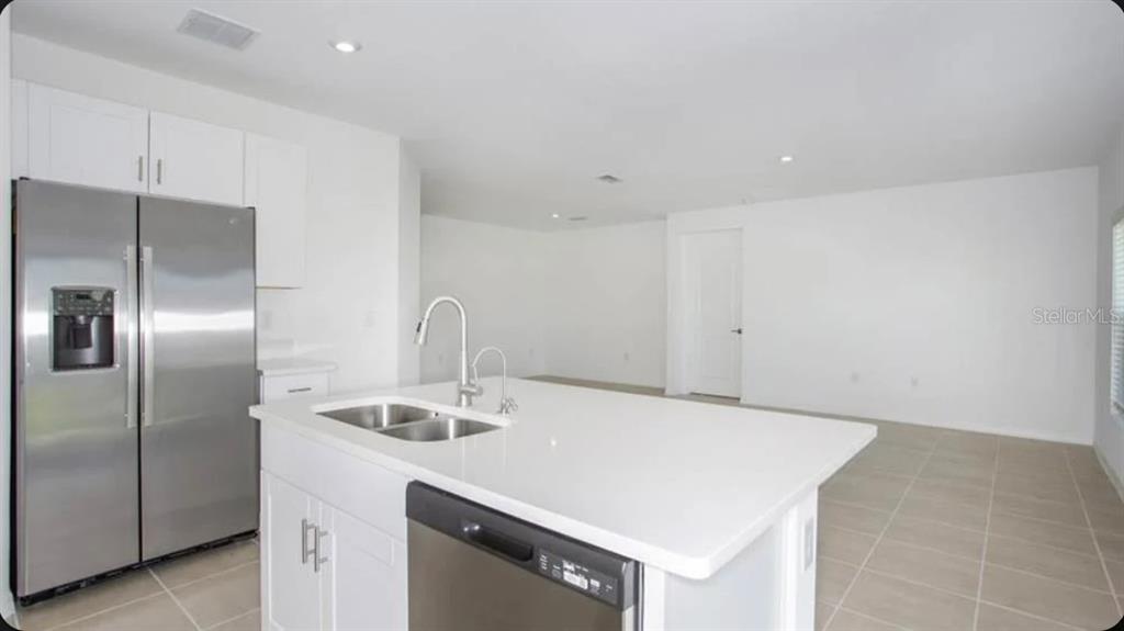 A modern kitchen features white cabinets, stainless steel appliances, and a central island with sink — 13317 COMMONS AVENUE, PARRISH, FL