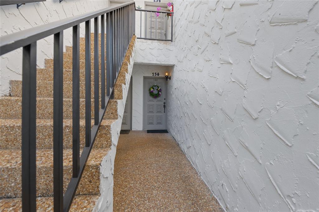 An outdoor staircase leads to a landing with two gray doors and textured walls — 1555 TARPON CENTER DRIVE UNIT 156, VENICE, FL