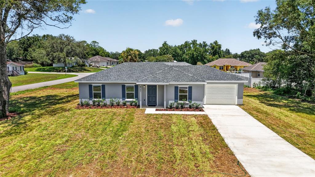 A single-story house with a gray exterior, dark shutters, and a concrete driveway — 6747 SW 86TH PLACE, OCALA, FL